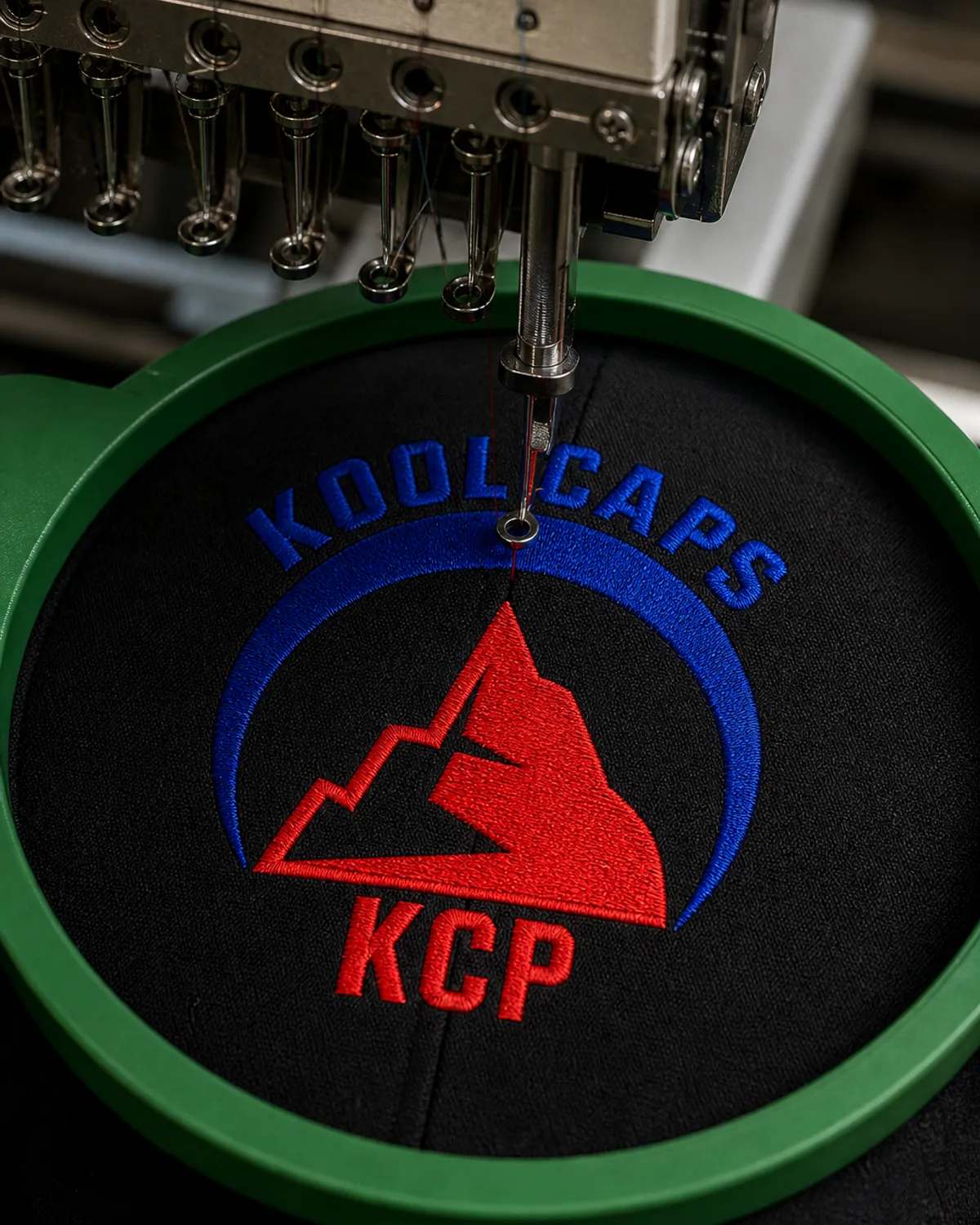 Detalle macro del bordado del logotipo de Kool Caps sobre una gorra negra
